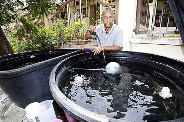 A neighbourhood guard fills up the water tubs in Rizal's house. Photo from thestar.com.my