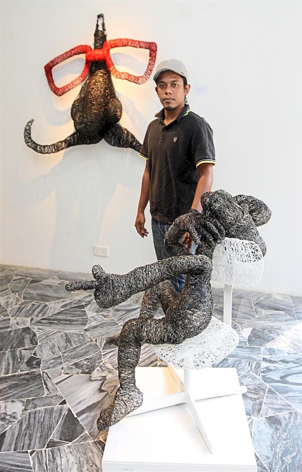 Jamil Zakaria posing with his steel wire art. Image from The Star.