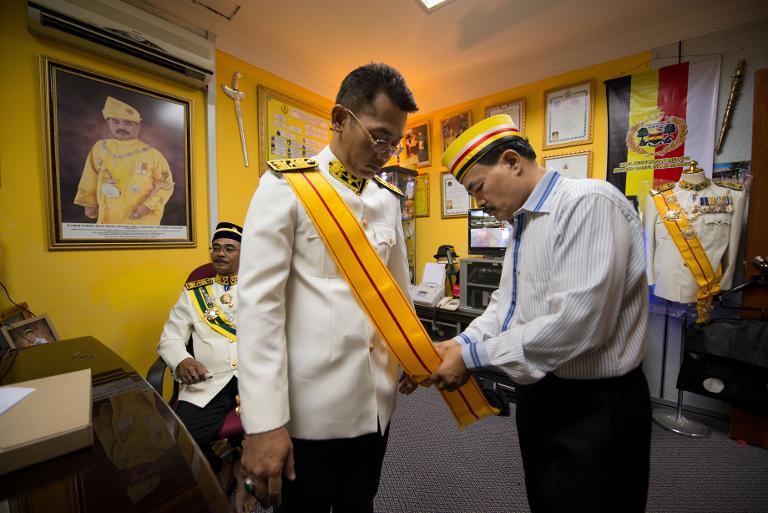 Noor Jan adjusts an official dress for title 'Datuk' at his palace. Image from Mohd Rasfan, AFP Photo on Says.