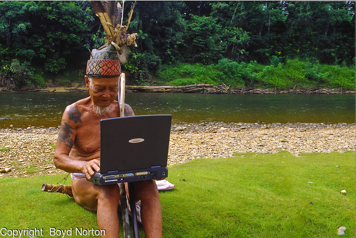 Even headhunters have to keep ahead. Iban elder and laptop, Iban tribe, former headhunters, rainforest Skrang River, Sarawak, Borneo, Malaysia.