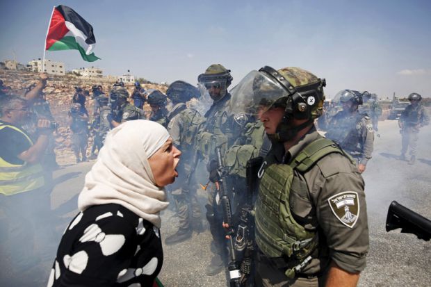 A Palestinian woman arguing with an Israeli border policeman, in West Bank, Palestine. Img from Times Higher Education.