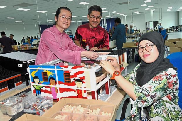 Siti Fatimah with Pang (left) and Lee assembling a LEGO model. Image from The Star