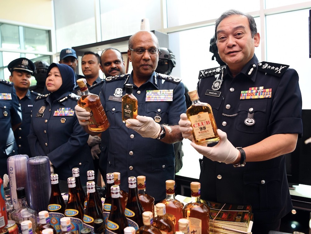 Customs holding seized liquor. Image from The Malay Mail.