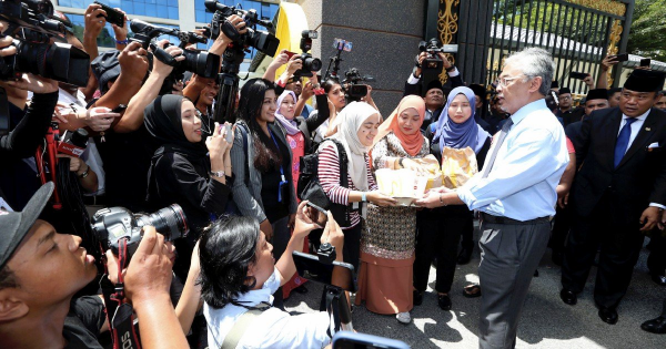 Yang di-Pertuan Agong distributing McDonald's to journalists outside Istana Negara. Image from NST